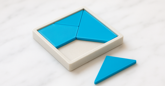A shallow tray holding three flat cyan geometric tiles with one piece left outside and a visible gap