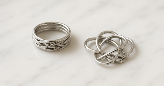 A six-band puzzle ring assembled, beside a second one fallen into loose bands